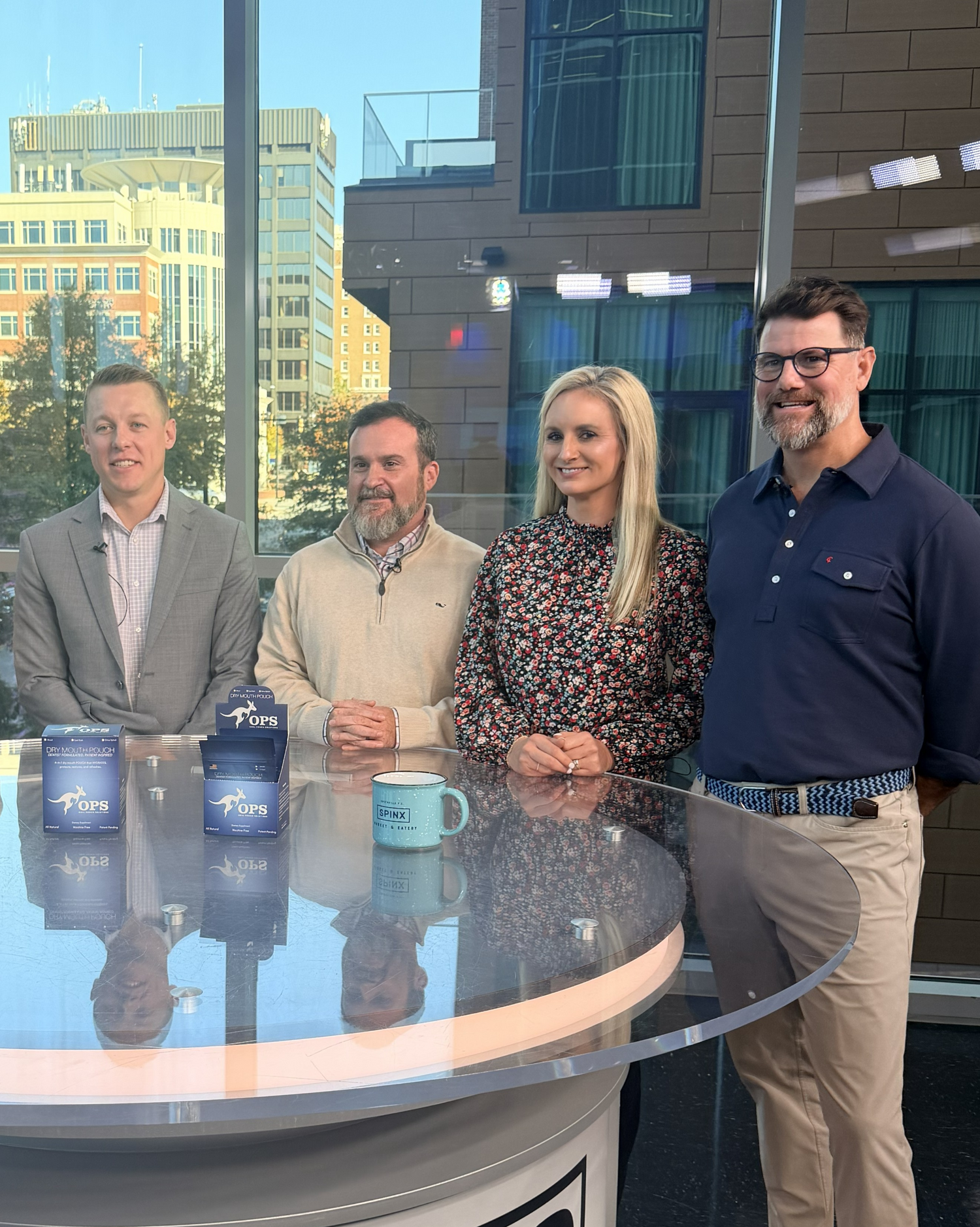 Founders of Oral Pouch Solutions standing around a news table with coffee cups discussing dry mouth product